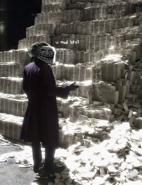 A person wearing a dark coat and a troll face mask stands in front of massive stacks of bundled cash, with loose bills scattered on the floor.