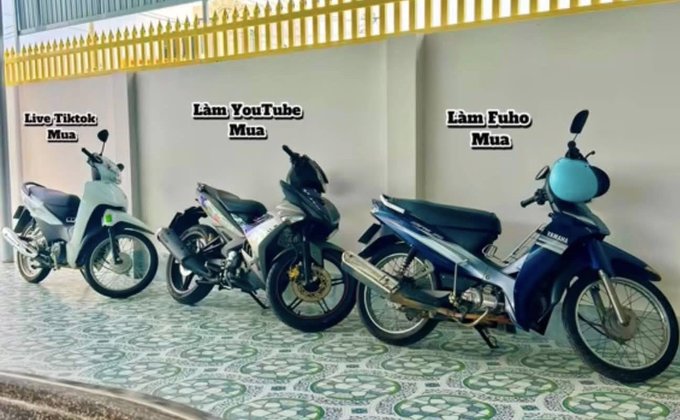 A meme showing three motorcycles parked outside, labeled with text: 'Live/Tiktok Mua' (cheapest, missing parts), 'Làm YouTube Mua' (mid-quality), and 'Làm Fuho Mua' (the fanciest one).