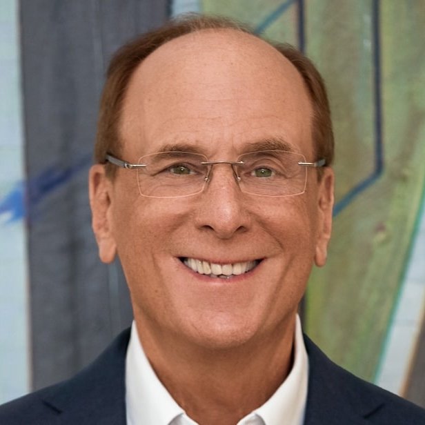 A smiling portrait photo of an older man with glasses, a receding hairline, wearing a dark suit jacket and white shirt.