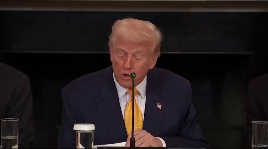 The image shows a man sitting at a table with his hands clasped together while speaking into a microphone, possibly delivering a speech or addressing an issue. The man is wearing a suit and tie, which suggests that he might be a political figure such as President Trump. In the background, there are other people present who appear to be listening to him. 

The image also contains text that reads "NEVER SELL YOUR BITCOIN", which seems to be related to Bitcoin or cryptocurrency in some way. This could possibly be an advertisement for Bitcoin or a warning about the risks of selling Bitcoins.