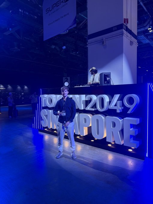 A man poses in front of a large 'TOKEN2049 SINGAPORE' illuminated sign at the conference venue.