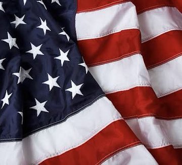 A close-up of the American flag fills the frame, its stars and stripes shown in vivid detail. The image symbolizes the U.S. side of the historic cross-border tokenized deposit payment between Singapore and the United States.