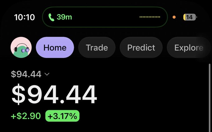 A mobile trading app interface showing a portfolio value of $94.44 (up +$2.90 or +3.17%) at 10:10, with navigation tabs for Home, Trade, Predict, and Explore.
