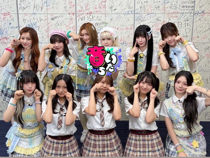Ten members of the K-pop group UNIS pose together in coordinated plaid skirts and school-uniform-style outfits, with a colorful logo reading "音いたち" (Otoitachi) overlaid at the center, promoting their upcoming late-night appearance on Kantele's broadcast.