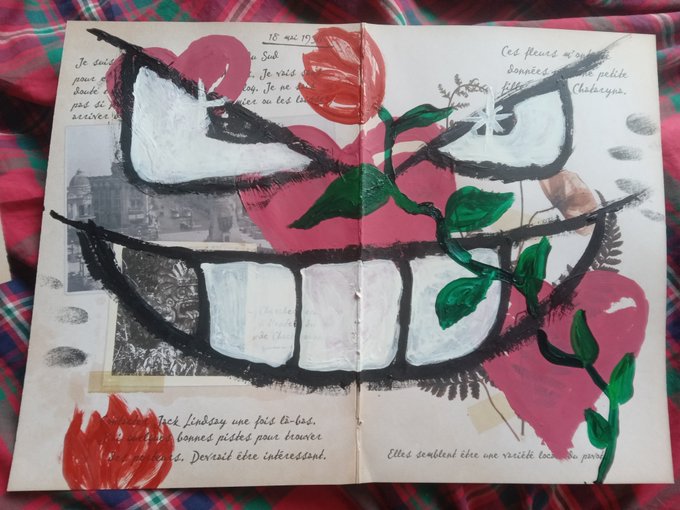 An open sketchbook displays a surreal painted face with an exaggerated toothy grin and red flower, dated '18 mai 19'.
