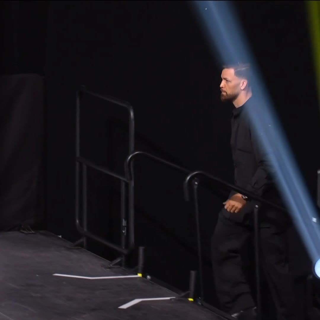 A bearded fighter in a black suit walks down a ramp under a spotlight, seemingly making his entrance to the arena prior to his bout at UFC 331. The image sets the stage for the upcoming clash between Arman and Ruffy as referenced in the post.