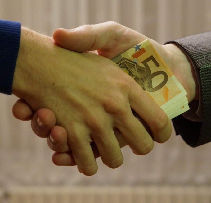 Close-up of a handshake where one person is secretly passing a 50 Euro banknote to the other during the greeting.
