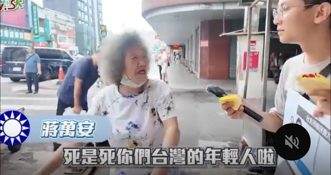 The image shows an elderly woman being interviewed on a street by a man holding a microphone and a piece of food, with a blue graphic labeled "蔣萬安" (Jiang Wan-an) and a subtitle reading "死是死你們台灣的年輕人啦" (Death is [on] your young people in Taiwan), relating to the post text "我那死老人比山多的國家⋯⋯" which comments on the elderly individual.