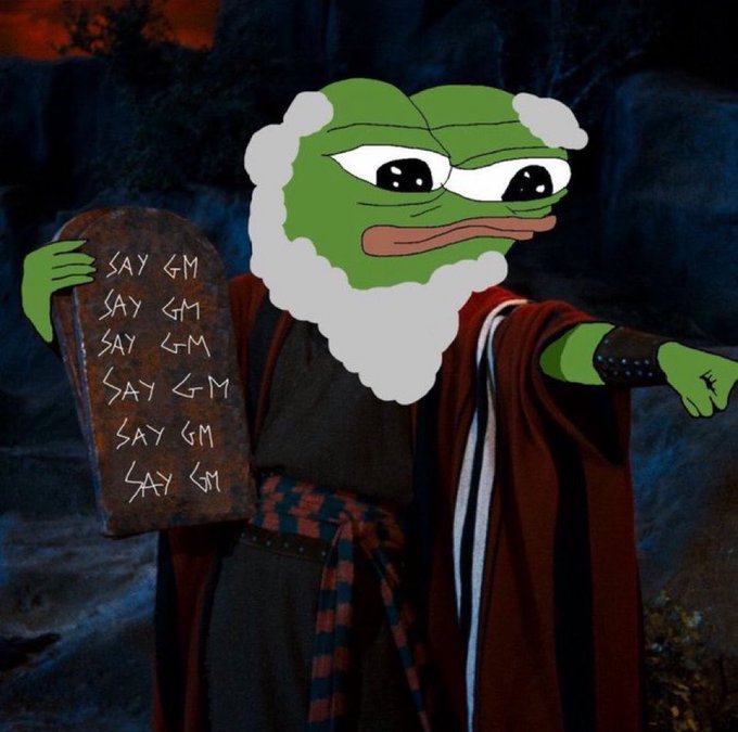 A Pepe the Frog meme edited with a long white beard and robes, holding a stone tablet inscribed with 'SAY GM' repeated six times while pointing forward in a dark setting.