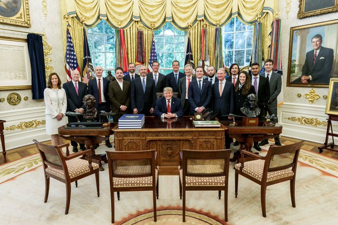 President Donald Trump sits at the center of the Resolute Desk in the Oval Office, flanked by a group of officials, with crypto industry leader Brad Garlinghouse positioned among the lineup near Trump and SEC Chair Paul Atkins and "Mr. Selig," as referenced in the post celebrating the symbolic photo marking Ripple's role in the future of crypto regulation.