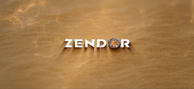 The text "ZENDOR" is displayed in white letters on a sandy beach surface, with the 'O' replaced by a circular emblem.