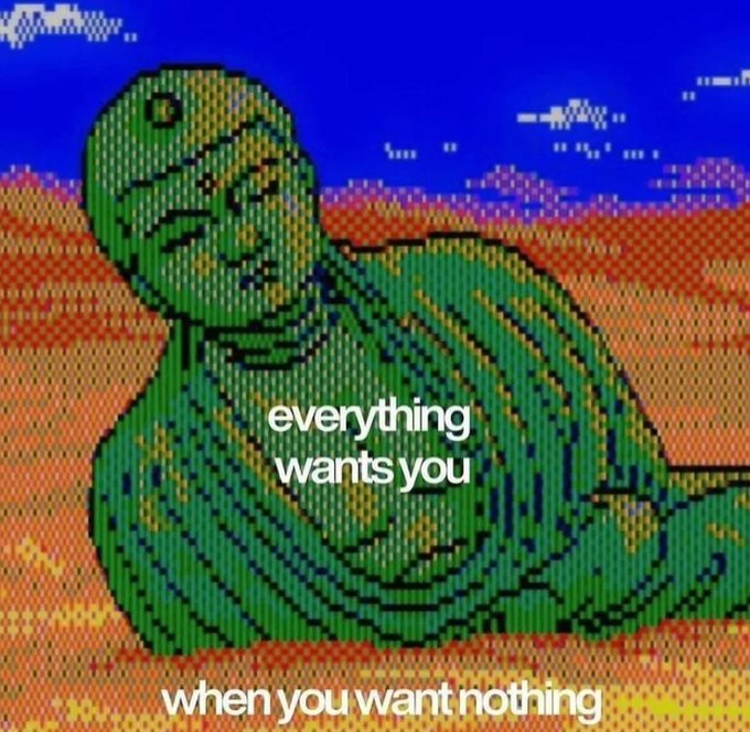 Pixel art of a green, Buddha-like figure resting on a reddish-orange textured surface under a blue sky, with the text 'everything wants you' and 'when you want nothing' overlaid.
