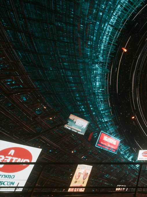 A low-angle photo looking up at a curved glass and steel ceiling structure with circular architectural elements, featuring illuminated advertising displays including 'BETTINO' and 'IBARAKI' signs.