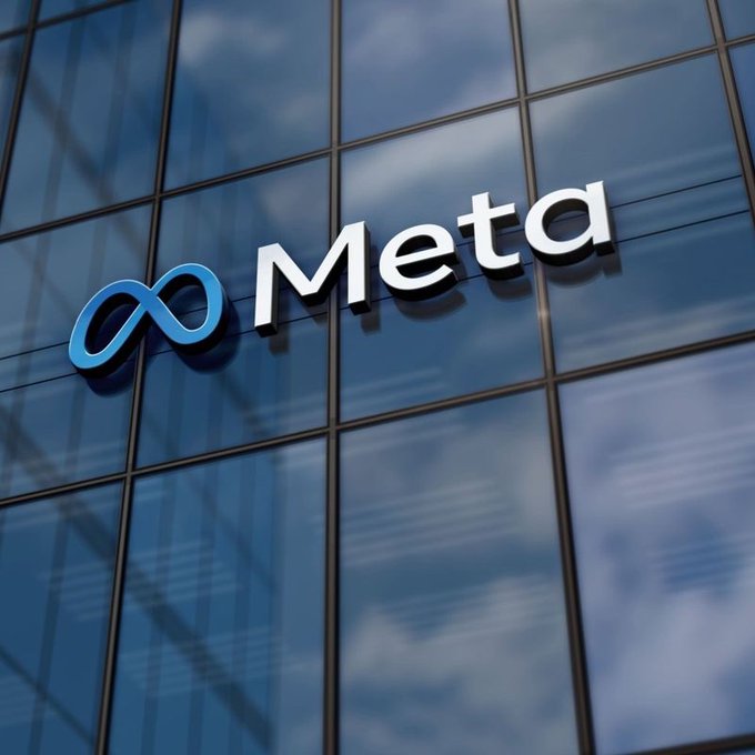 The image shows the "Meta" logo prominently displayed on the glass facade of a corporate building, with the company's signature infinity symbol in blue alongside the white "Meta" wordmark, reflecting the sky in the windows. This visual connects to the post by symbolizing Meta's recent upward momentum driven by Muse AI developments and a bullish Wells Fargo target increase, suggesting the tech giant's AI-driven rally may have further room to run.