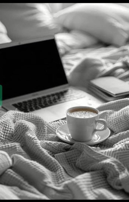 The image features a laptop computer placed on top of a bed with a white cup of coffee sitting next to it. The scene suggests that someone might be working or studying from home, enjoying their coffee while using the laptop for various tasks such as browsing the internet, writing, or watching videos. The focus is on the combination of technology and comfort in this setting, emphasizing the importance of creating a cozy environment for productivity and relaxation.