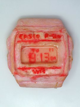 A digital watch displaying "4:13" is encased in pink, flesh-like textured material with red text reading "Castro P-340" and "9mg THC," referencing the post's description of the 2021 work "Untitled (9)" by Kim Asendorf, which parodies a Barbie-themed gummy edible infused with THC.
