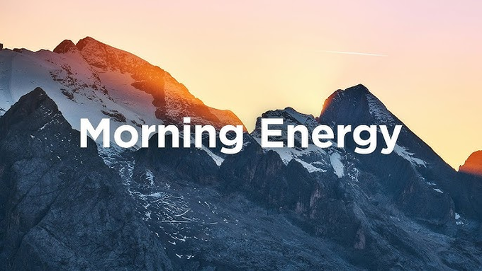 A scenic mountain landscape photograph featuring snow-capped peaks bathed in warm sunrise light under a pastel sky, overlaid with the white text 'Morning Energy'.