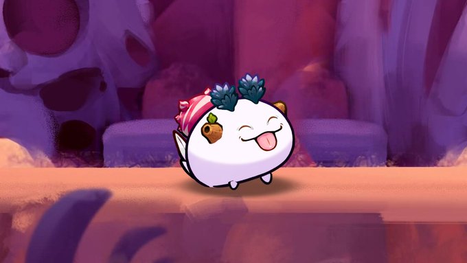 A cheerful Axie creature with a candy-striped strawberry on its head and a happy open-mouthed expression stands in a rocky, purple-hued landscape, fitting the festive Christmas theme mentioned in the post about a new owner receiving this holiday-themed pet.