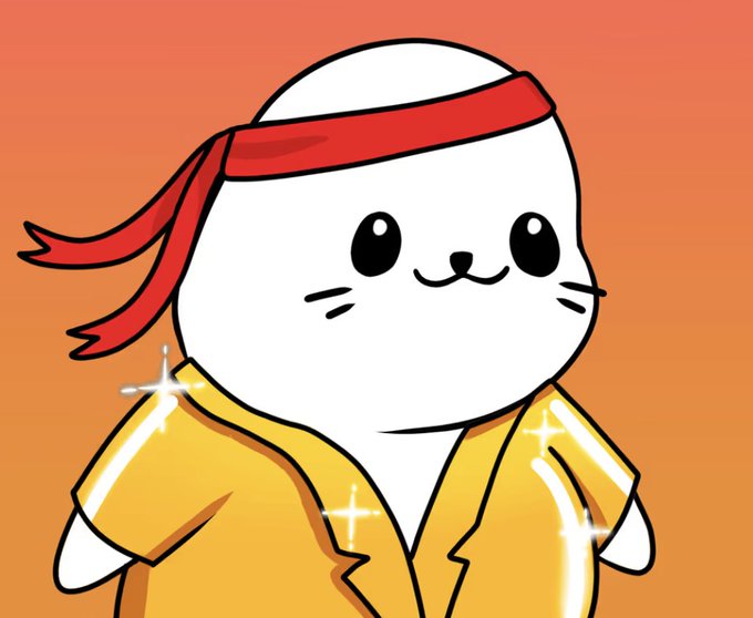 A cute white cartoon seal character wearing a red headband and a shiny yellow martial arts-style robe stands against an orange background, with sparkle effects highlighting the garment. The image relates to the post by showcasing one of the Sappy Seals NFT characters in a playful, stylized pose that reflects the fun, community-driven spirit of the collection.