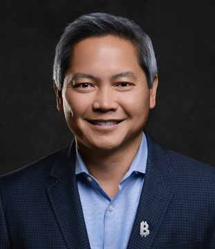 In this image, Phong Le, CEO of Strategy, wears a suit with a Bitcoin logo lapel pin, illustrating his company's commitment to supporting the BTC ecosystem as mentioned in the accompanying post.