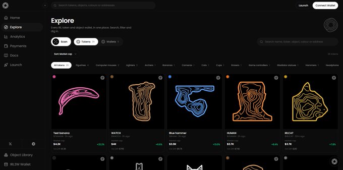 The image displays an IRL token collection featuring scanned real-world objects—including a "Test banana" at $4.2K, "WATCH" at $4K, "Blue hammer" at $3.8K, "HUMAN" at $3.7K, and "WILCAT" at $3.2K—each with unique neon-styled outline designs, reflecting the post's highlight of 80 objects scanned and 26 IRL tokens launched on the platform.