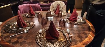 A beautifully set round dining table with deep red napkins and patterned plates awaits guests at a StellarOrg networking event, where attendees gather to connect and discuss opportunities in emerging technologies.