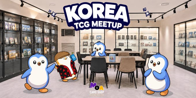 The image shows the interior of MOA Card Shop in Korea, featuring trading card displays on the walls and a central table, with three Pudgy Penguins characters posing in the foreground under a "KOREA TCG MEETUP" banner. This complements the post announcing the shop's opening and the launch of the KAKAWOW PHANTOM Pudgy Penguins collaboration for the Korean community.