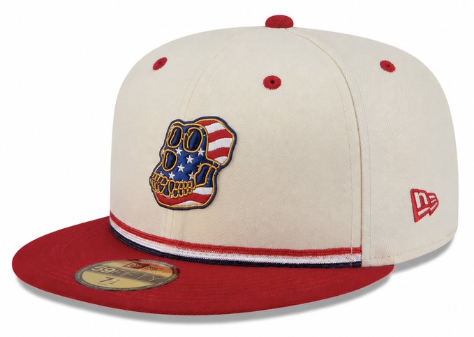 The image features a white baseball cap with red trim, adorned with an American flag design on the front. The hat has a band that matches the color of the trim, creating a cohesive look. The hat appears to be made from high-quality materials, suggesting it is designed for durability and comfort.