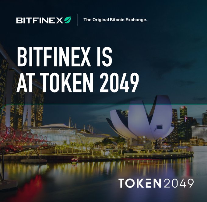 An advertisement for Bitfinex at Token 2049, featuring the Singapore skyline at night with the ArtScience Museum and Marina Bay Sands visible, with text reading 'BITFINEX | The Original Bitcoin Exchange' and 'BITFINEX IS AT TOKEN 2049'.