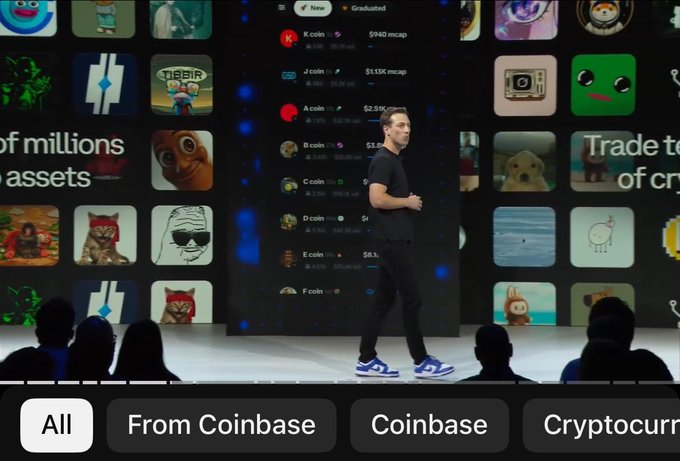 The image shows a man standing at a podium, giving a presentation or speech. He appears to be wearing a black shirt and blue jeans. The background of the image features a large screen displaying various images related to cryptocurrency, such as logos for Coinbase and Cryptocurren. The text on the screen reads "From Coinbase coinbase Cryptocurren".