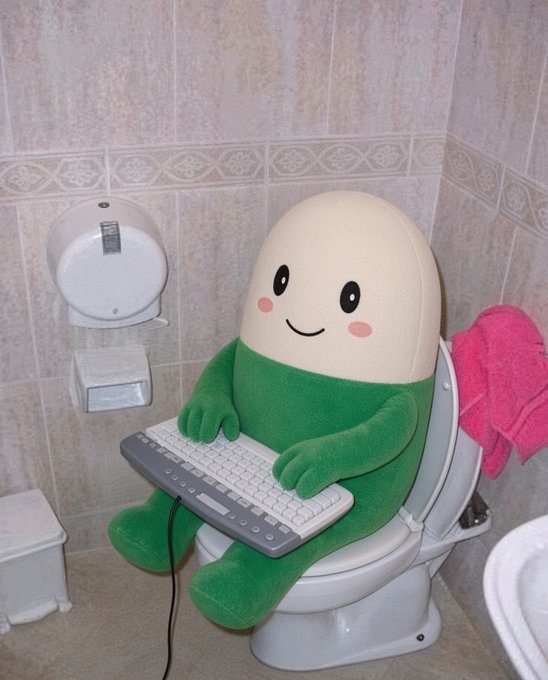 A plush green and cream character toy sitting on a toilet, holding a computer keyboard on its lap, in a tiled bathroom setting.