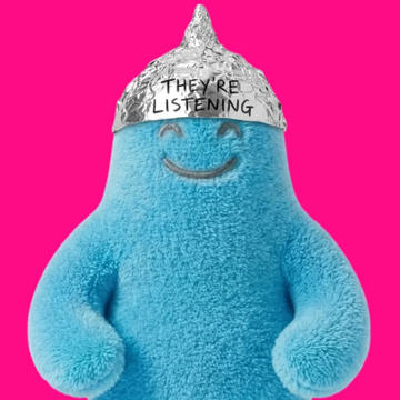 A blue plush toy wearing a tinfoil hat with the text "THEY'RE LISTENING" against a bright pink background.