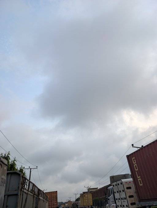 A cloudy, overcast sky stretches above an industrial scene featuring shipping containers and a large gold shipping container marked "GOLD."