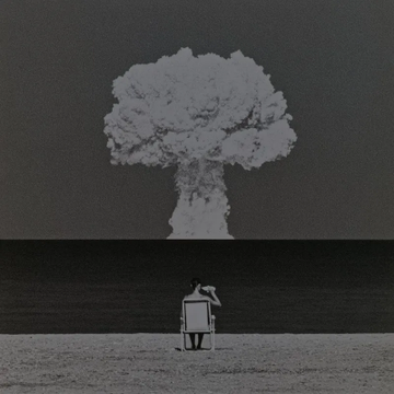 A surreal image showing a small figure standing on a chair watching a massive mushroom cloud explosion rise against a dark sky.