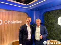 Two men posing for a photo at an event, with 'Chainlink' visible on the wall behind them and a 'Rollup' logo in the bottom right corner.