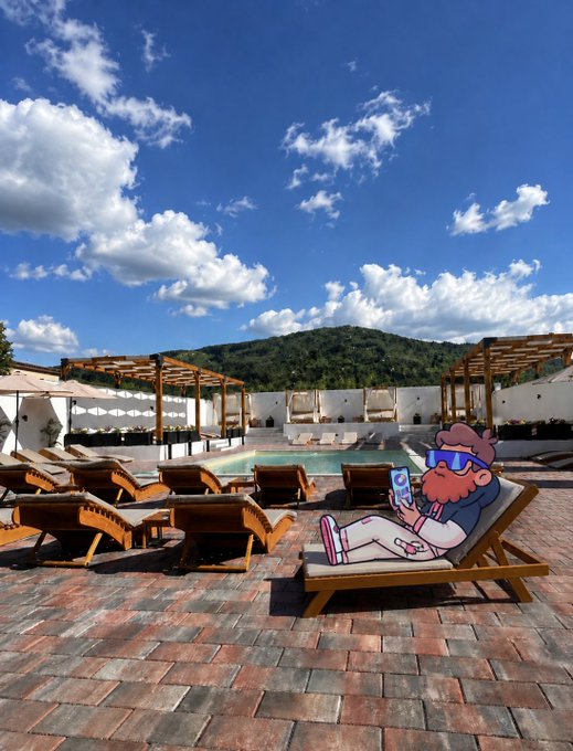 An outdoor poolside scene at a resort with wooden lounge chairs and cabanas under a blue sky with white clouds, featuring a cartoon character with purple hair and sunglasses relaxing on a lounger while using a smartphone.