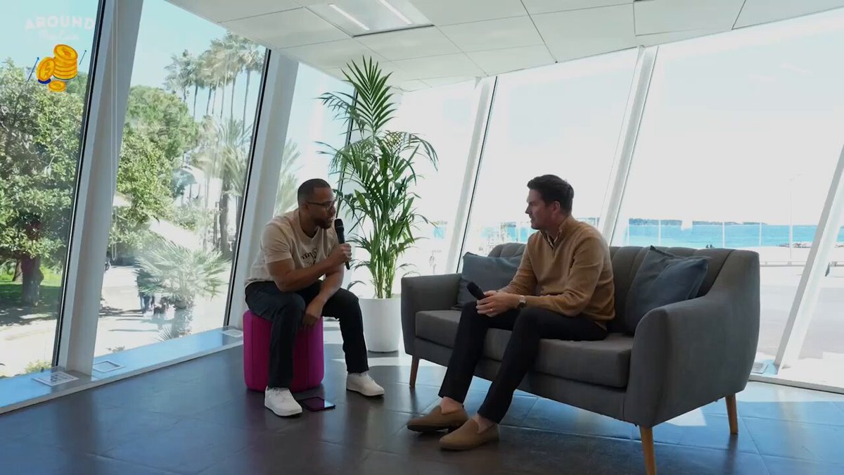 The image shows two men sitting on a couch, engaged in conversation with each other. The room they are in has large windows that provide natural light, creating a comfortable atmosphere for their discussion. A potted plant can be seen nearby, adding a touch of greenery and life to the space. The post about why we still pay to rent someone else's property is related to this scene because it highlights how people used to own their homes or land instead of renting them out like they do today.

The image also contains text that reads "@kylejenke breaks it down on the @aroundthecoin podcast." This suggests that there might be a podcast episode featuring the conversation between the two men, discussing the concept of renting property and its relevance in modern times.