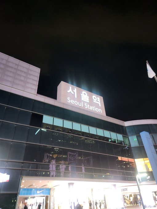 A nighttime photo shows the illuminated exterior of Seoul Station with its Korean and English signage visible against the dark sky.