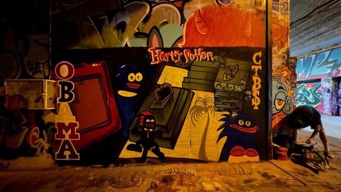 A graffiti-covered wall features "Harry Potter" text along with cartoon monster characters and the letters "OBAMA" and "CRIBBS."