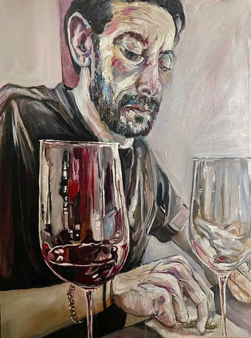 An oil painting portrait of a bearded man with closed eyes, wearing a dark shirt, sitting behind two wine glasses—one filled with red wine and the other empty—with his hands resting on a table.