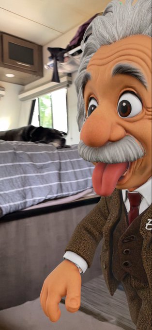 An animated 3D avatar of an elderly man with grey hair, sticking out his tongue, positioned inside an RV with a dog sleeping on a bed in the background.