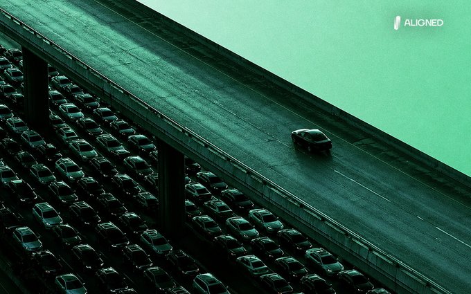 A lone car speeds along an empty overpass above a sea of gridlocked traffic, illustrating the post's message about bypassing congestion—one vehicle gliding free while countless others sit stuck below. The "ALIGNED" logo appears in the top right corner, reinforcing the brand's visual metaphor for proof aggregation over individual verification.