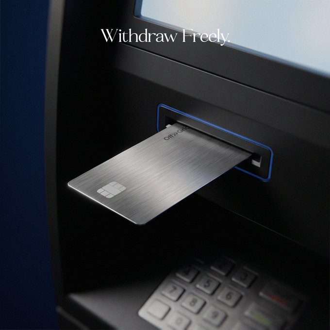 A brushed metal credit card partially emerges from the slot of a sleek ATM, with the phrase "Withdraw Freely." displayed on the screen above. The post's teaser "Something new is loading..." suggests the card's reveal hints at an upcoming financial product or service launch.