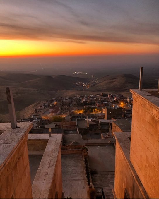 A sunset view overlooks a hillside town nestled in the valley below, with warm golden light fading into dusky purples as city lights begin to twinkle in the distance. The serene evening landscape contrasts with the post's focus on the Quip quantum compute marketplace, perhaps evoking a quiet moment of reflection on emerging tech horizons.
