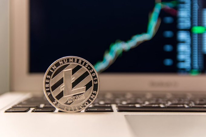 A physical Litecoin coin displaying "VIRES IN NUMERIS" and "2013" rests on a laptop keyboard, with a rising green trading chart visible on the screen behind it—visually reinforcing the post's thesis about $LTC being a reliable, long-standing crypto asset that consistently delivers value without needing flashy new narratives.