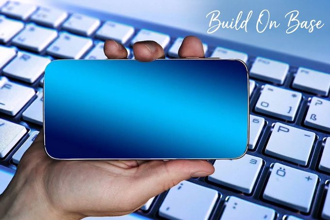 A hand holding a smartphone with a blank blue screen over a white keyboard, with the text "Build On Base" written in the upper right corner.