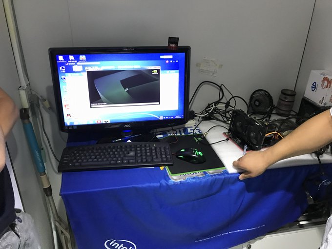A vintage photograph captures an early Zcash GPU mining setup with an AOC monitor displaying a desktop, alongside a keyboard, gaming mouse, and exposed graphics hardware on an Intel-branded tablecloth, illustrating the humble origins of ZEC mining at just ~300 Sol/s before modern ASICs like the Bitmain Z15 Pro achieved 840,000 Sol/s.