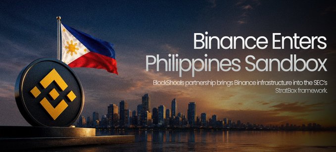The image features a large, colorful flag with the words "Binance Enters Philippines Sandbox" written below it. The flag has the colors of the Philippine flag - red, white, and blue. In front of the flag, there is a black coin that appears to be a Bitcoin token. Below the flag, there is text that reads: "BlackShoals partnership with Binance brings funds into the SDCs".