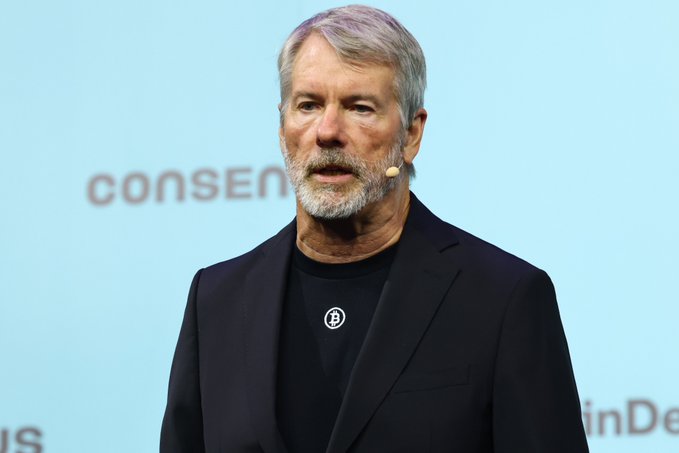 The image shows Michael Saylor, Executive Chairman of MicroStrategy, speaking at what appears to be the Consensus conference (with "Consensus" partially visible in the background). The caption directly relates to the post, as Saylor is a prominent Bitcoin advocate whose bullish outlook on BTC is being highlighted alongside the post's prediction of significant returns for various cryptocurrencies.