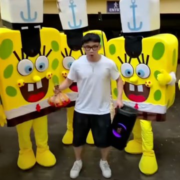 A young man poses with a tray of donuts and a black bucket between two large SpongeBob SquarePants mascots wearing white sailor hats with anchor emblems at what appears to be a convention or event. The post "we need dis in brypto" suggests fans want this entertaining SpongeBob-themed encounter to be recreated or available as NFT collectibles in the crypto space.